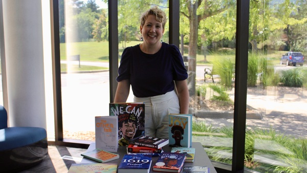 Melissa Brooks-Yip stands behind a table with diverse books on display.