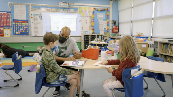 An adult paraprofessional helps a student