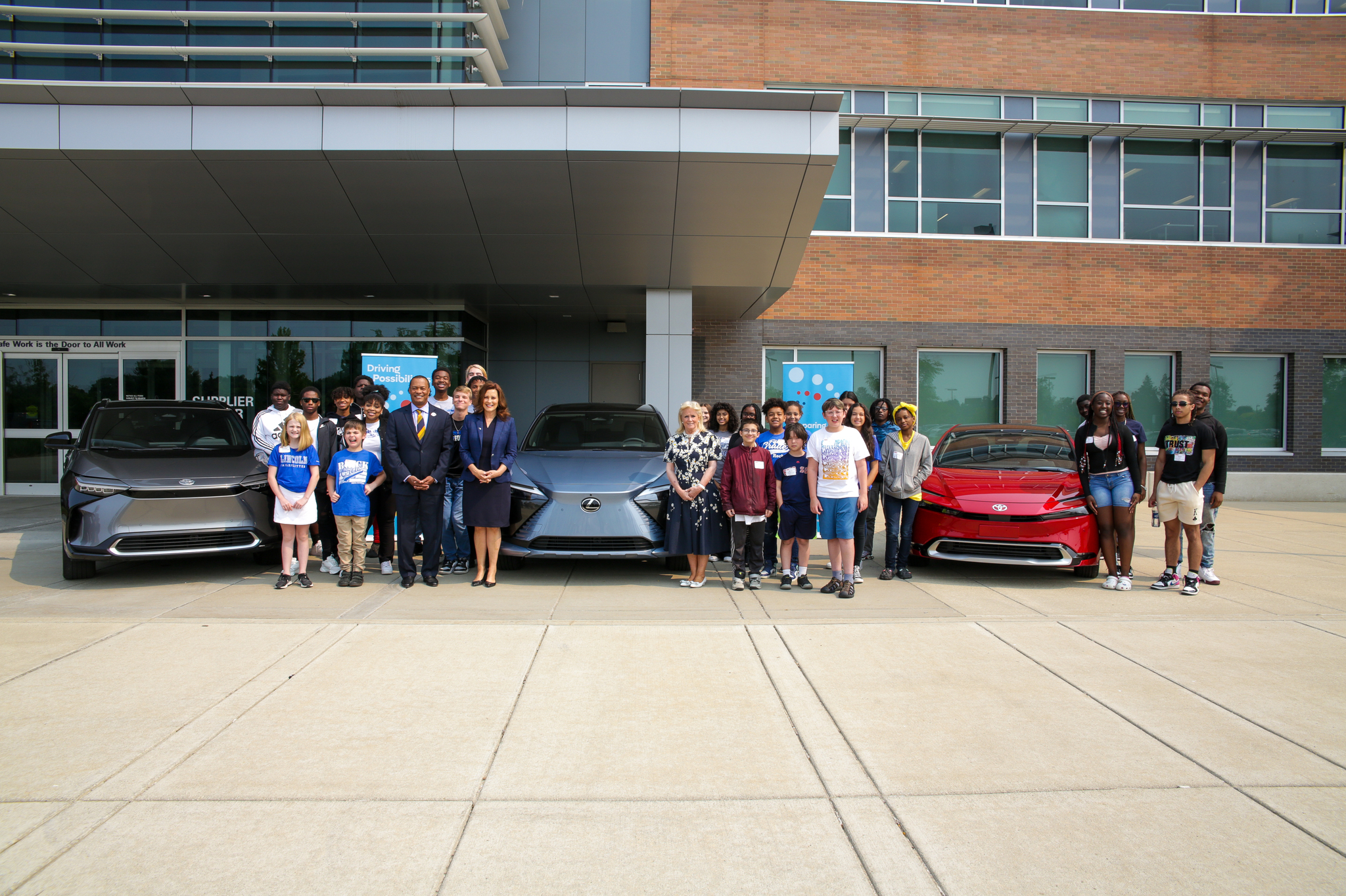 Students stand next to electric vehicles.