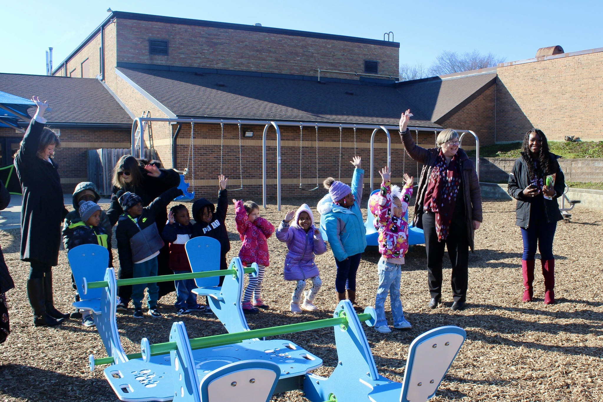 Children and adults stand in the middle of playground