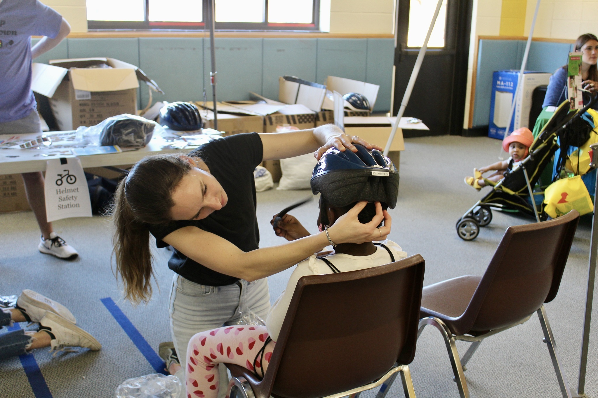 An adult woman fits a child with a bike helmet.